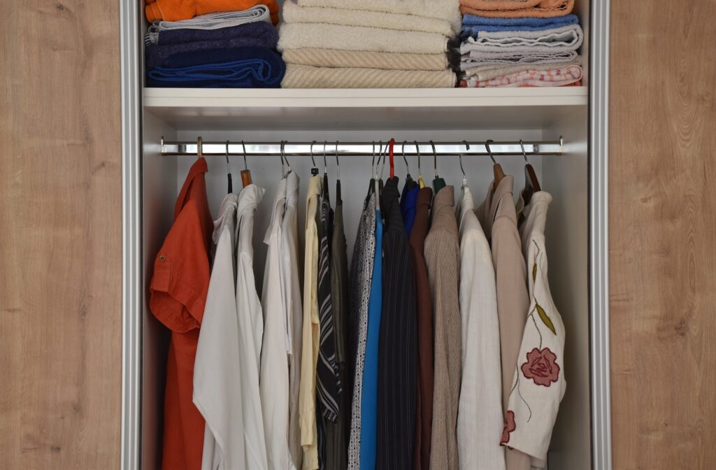Hangers and shelves with different clothes in wardrobe closet
